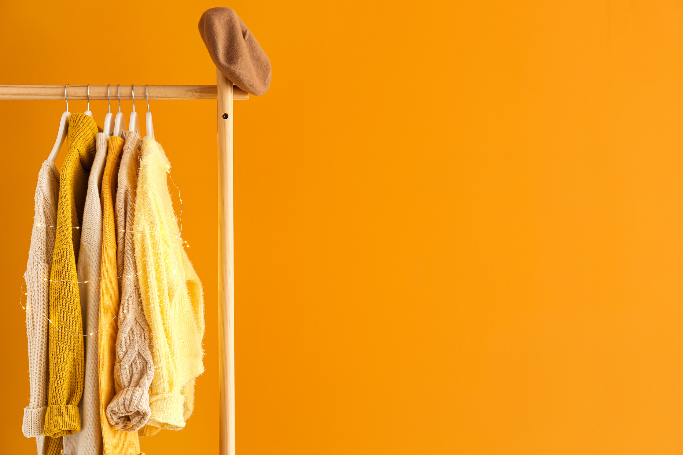 Rack with Winter Clothes on Yellow Background