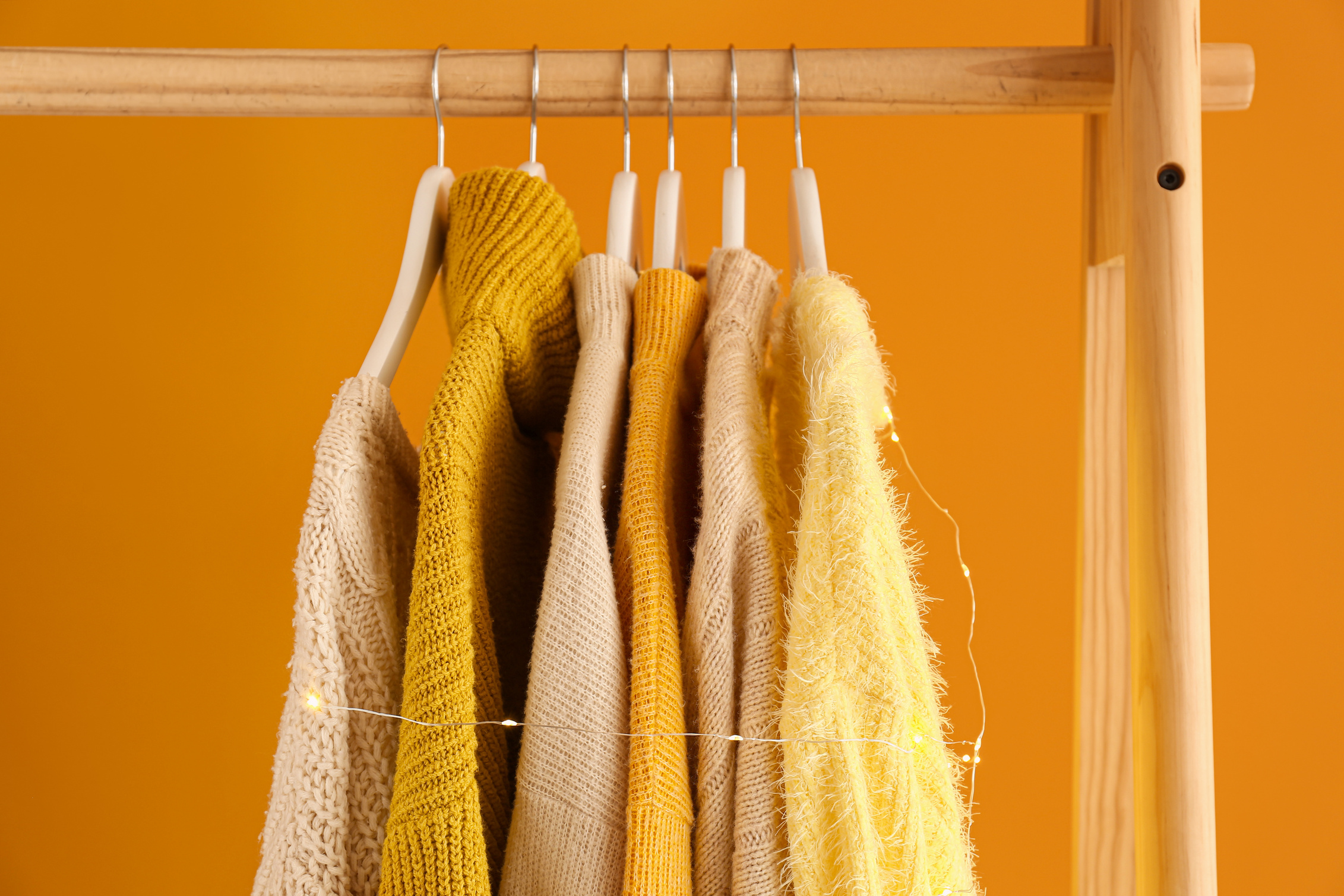 Rack with Winter Clothes on Color Background